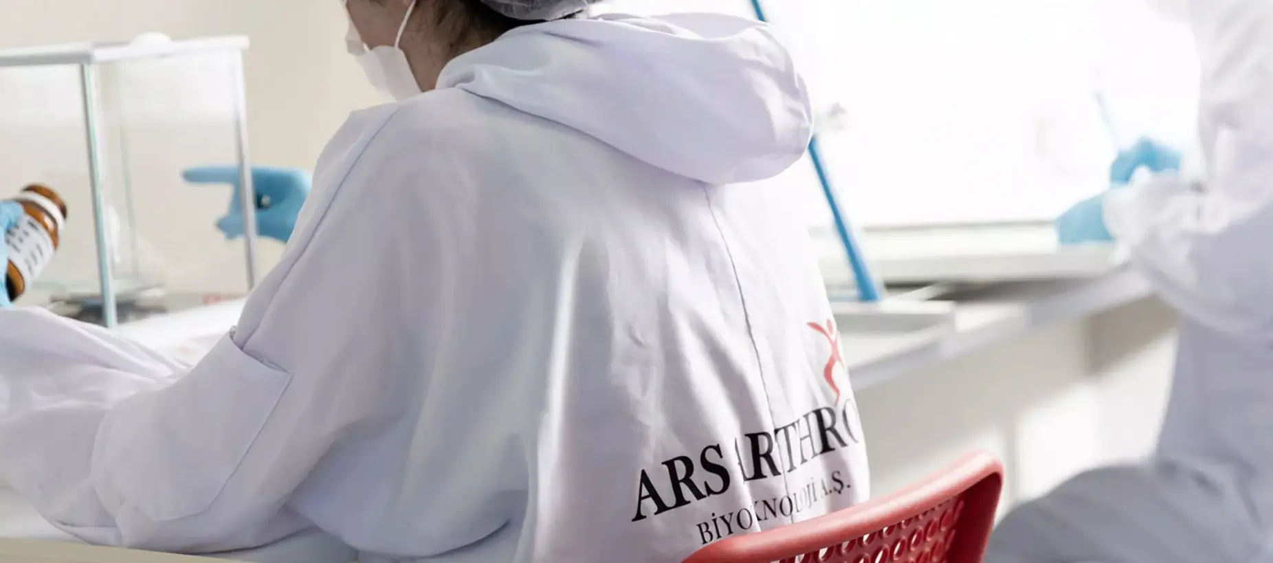 Sırtında Ars Arthro logosu olan önlükle çalışan araştırmacı